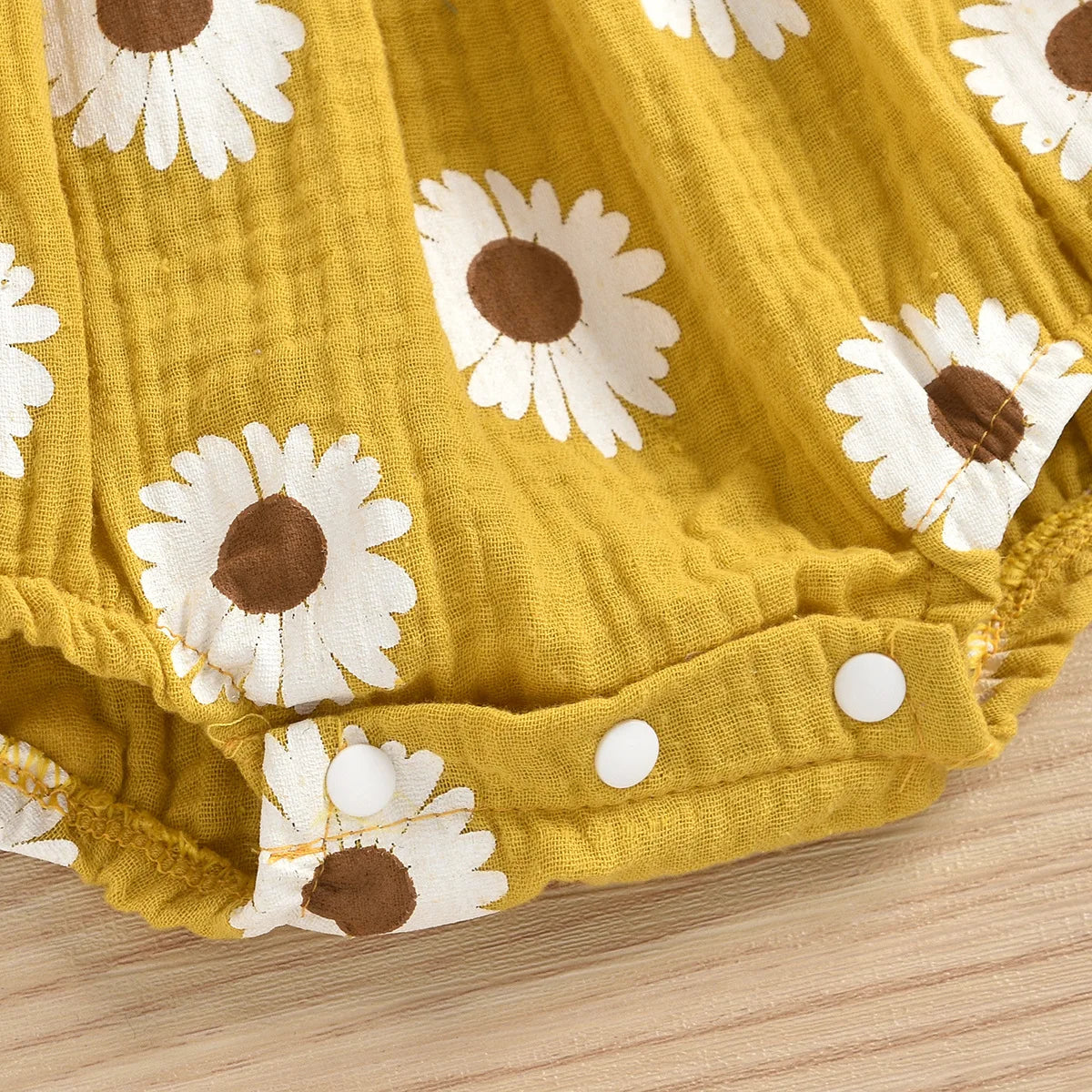Yellow cotton romper for a baby girl with a white and brown daisy floral print
