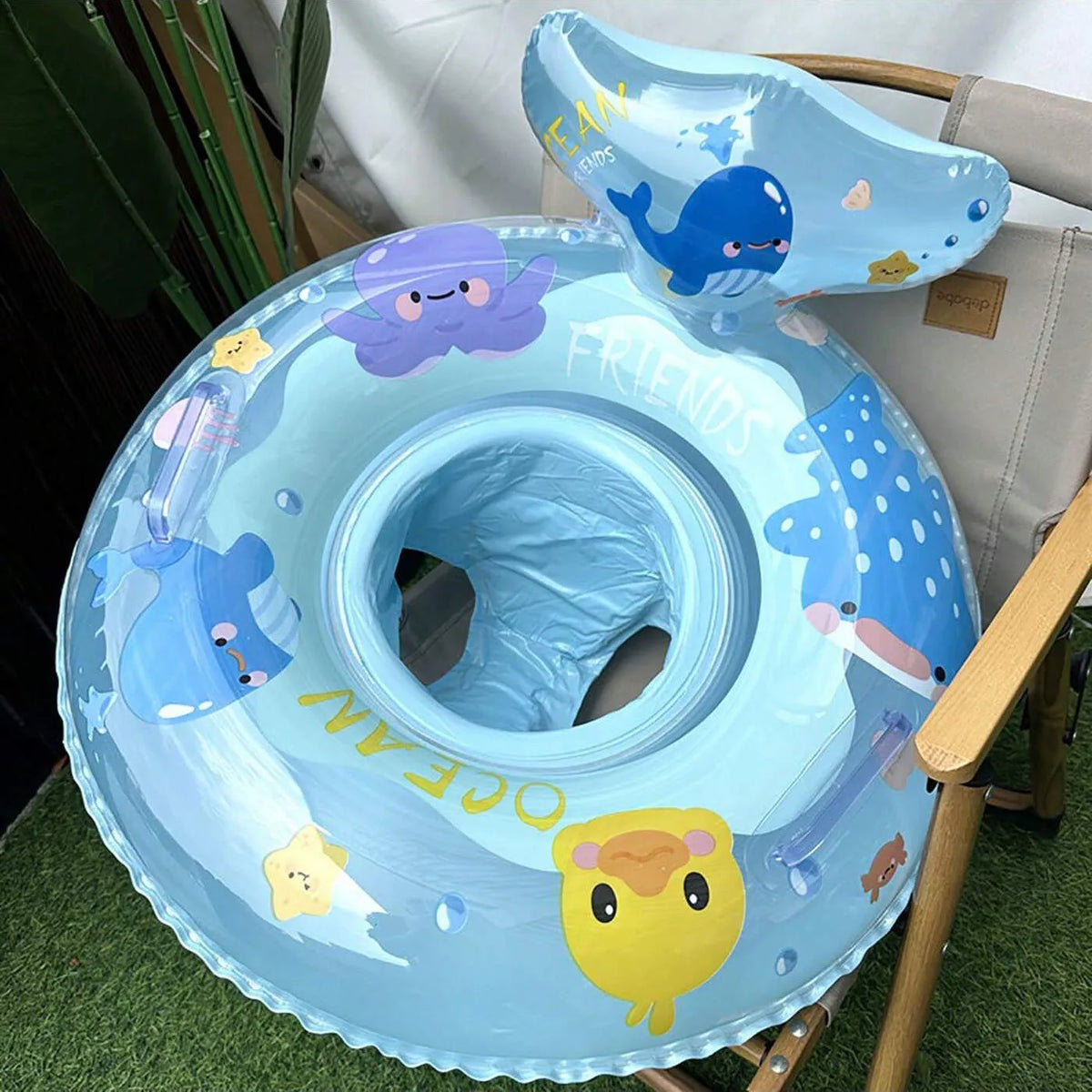 A light blue inflatable baby swim ring with a seat shaped like a whale and friendly sea creatures.