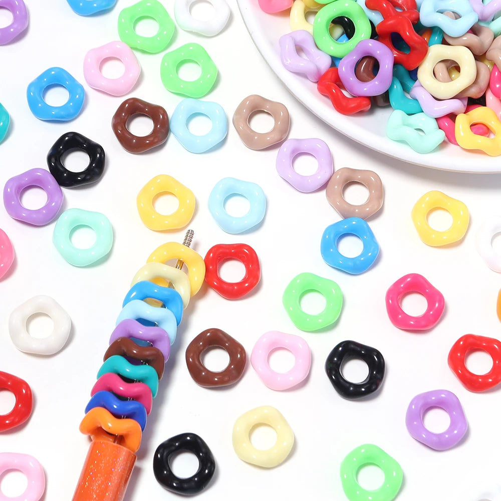 A collection of colorful acrylic doughnut spacer beads in various shades including pink, green, yellow, and black.