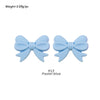 A pair of light blue silicone bow tie beads used for jewelry making and craft projects.