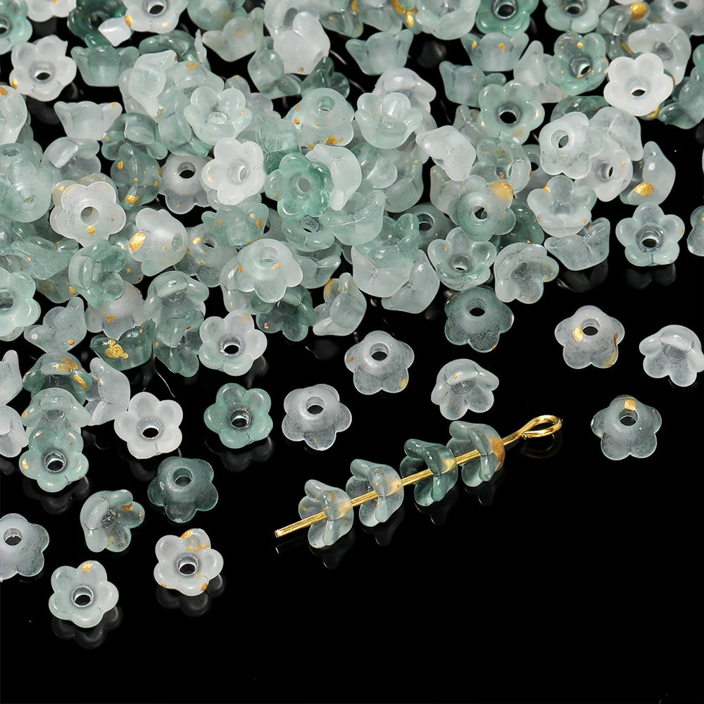 A pile of small, translucent green and clear bellflower acrylic beads for jewelry making.