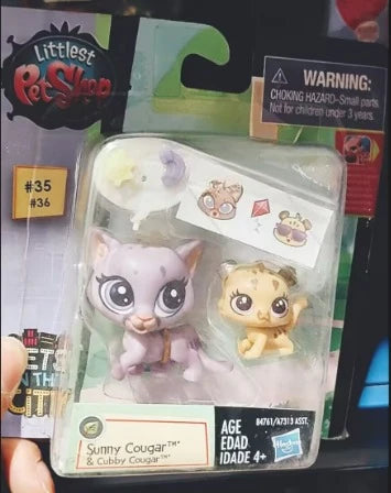 A plastic packaging shows three small purple and yellow animal figures, including a cat and a lion cub.