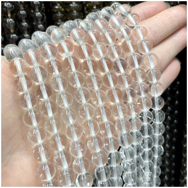 A hand holds a string of clear natural stone beads for DIY jewelry making.