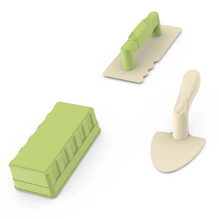 A green beach castle sand play set with a bucket and scoop resting on a light-colored surface.