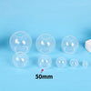A collection of clear silicone sphere molds of various sizes, including a 50mm mold, displayed on a light blue surface.