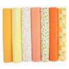 A pack of seven rolled cotton fabric squares in various stripes and patterns of yellow, orange, white, and green.
