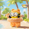 A yellow plush toy with large glasses and brown fur ears is shown in a tropical outdoor setting.