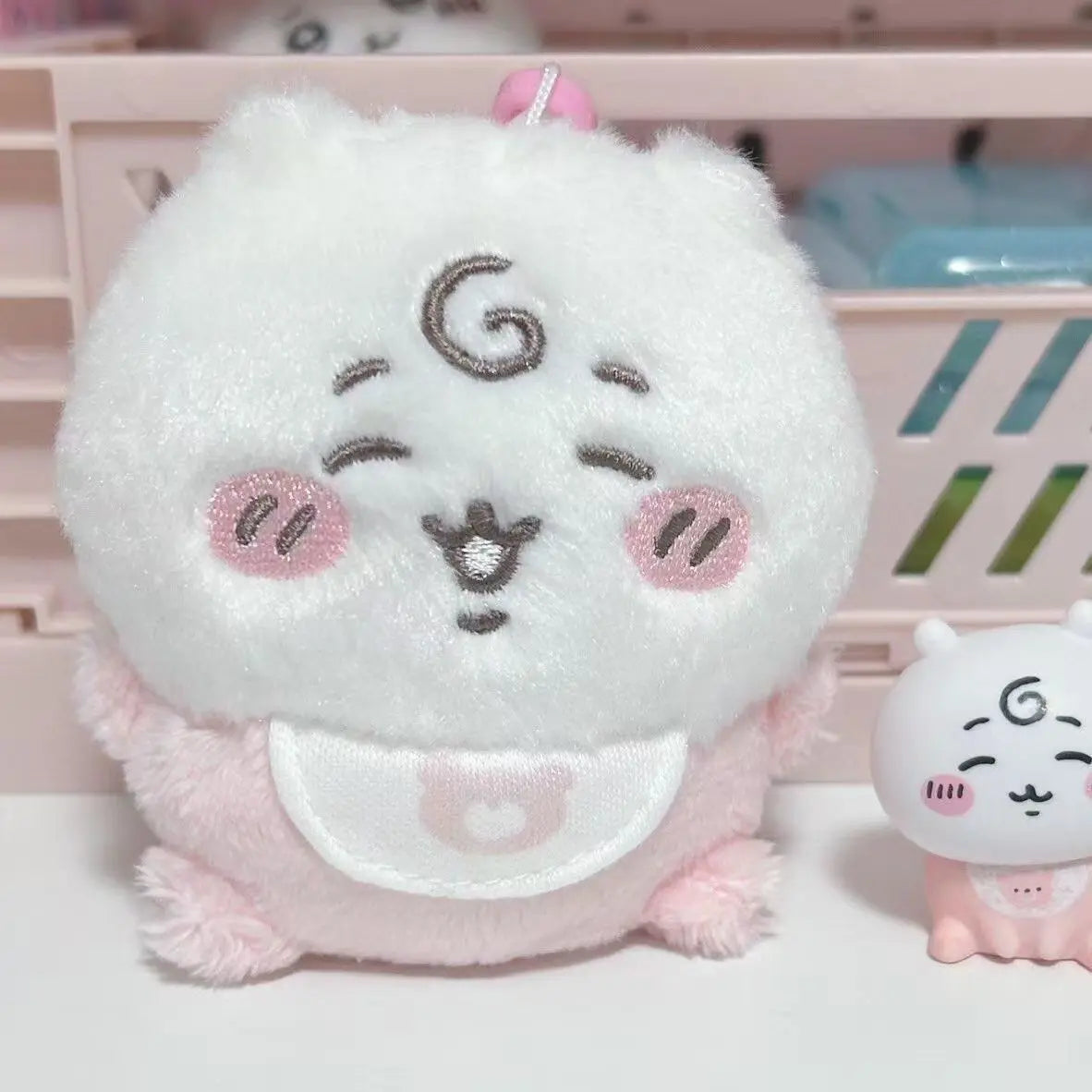 A set of three white and pink kawaii plush toys, including a large white cat face, a smaller white cat, and a pink plush.