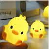 A hand holds a glowing yellow cartoon duck night light, illuminating a surface.