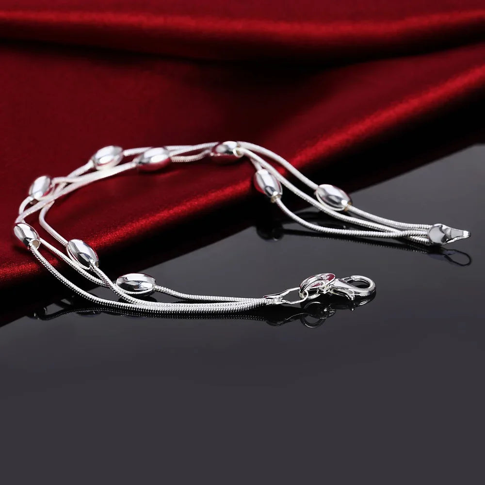 Elegant sterling silver snake chain bracelet for women displayed on a dark surface against a red velvet background