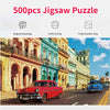 A colorful jigsaw puzzle featuring a street scene with historic buildings and a red classic car.