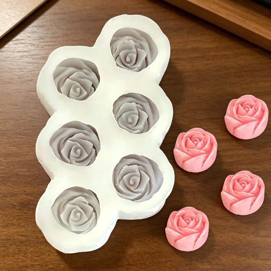 A white silicone mold set featuring multiple 3D rose flower shapes in gray and pink colors.
