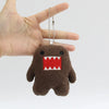 A small, dark brown plush toy shaped like a monster with a red toothy grin, attached to a silver chain.