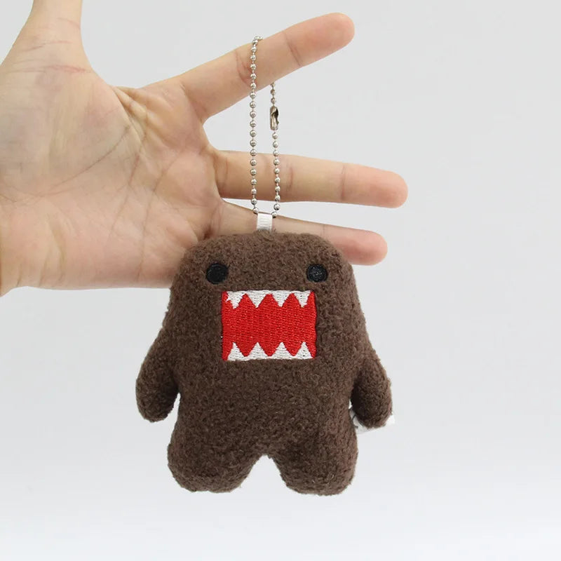A small, dark brown plush toy shaped like a monster with a red toothy grin, attached to a silver chain.