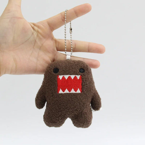 A small, dark brown plush toy shaped like a monster with a red toothy grin, attached to a silver chain.
