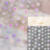 Sheet of nail art stickers featuring various pastel colored flowers, hearts, and butterflies on a translucent background