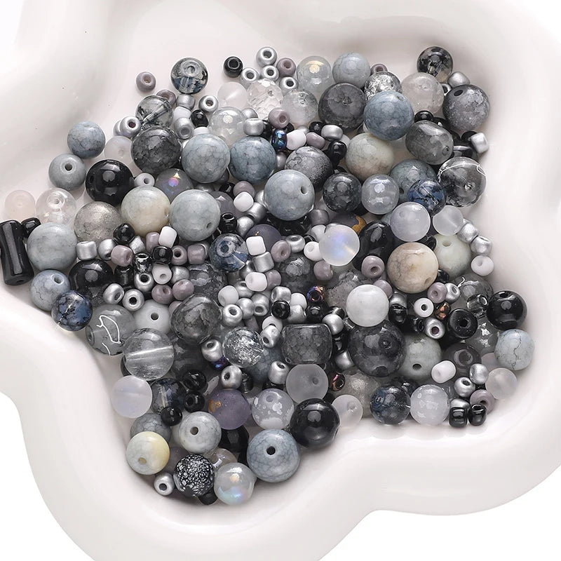 A pile of multicolored glass beads in various sizes and shades resting in a white bowl.
