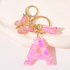 Gold initial A keychain featuring a pink butterfly charm and pink tassel.