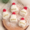 A set of mini knitted white hats with red pom-poms and gold lettering for Christmas doll dress-up accessories