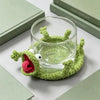 A handmade crochet lizard is shaped like a coaster, resting on a light green surface.