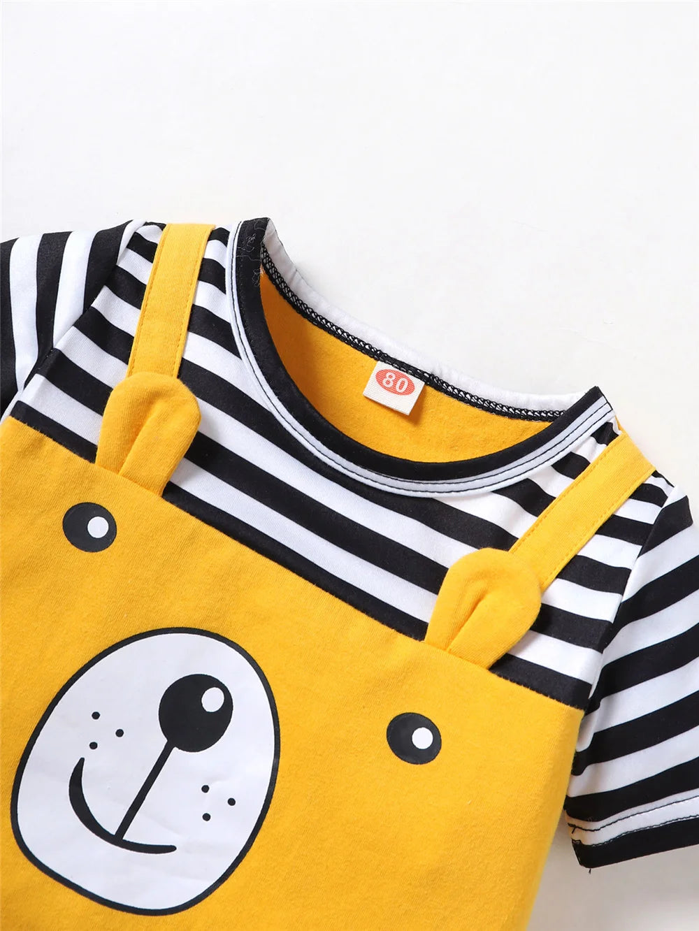 A yellow baby romper with black and white stripes and a bear face print.