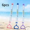 Three pull-back water guns in pink, blue, and purple are shown on a sandy beach near the ocean.