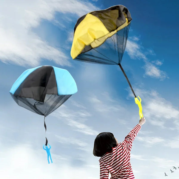 A child is flying a blue parachute toy against a bright blue sky.