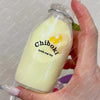 A hand holds a clear glass bottle filled with yellow liquid and a yellow squishy toy labeled Chiboki.