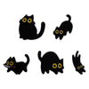 A set of four black cat enamel pins with glowing yellow eyes.