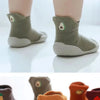 A set of soft-soled baby first walker socks shoes in various earthy tones including olive green, beige, and orange.