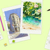 Watercolor paints, brushes, and sketchbooks featuring landscapes and nature scenes on a light green background.