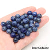 A handful of round blue sodalite beads is held in a person's hand.