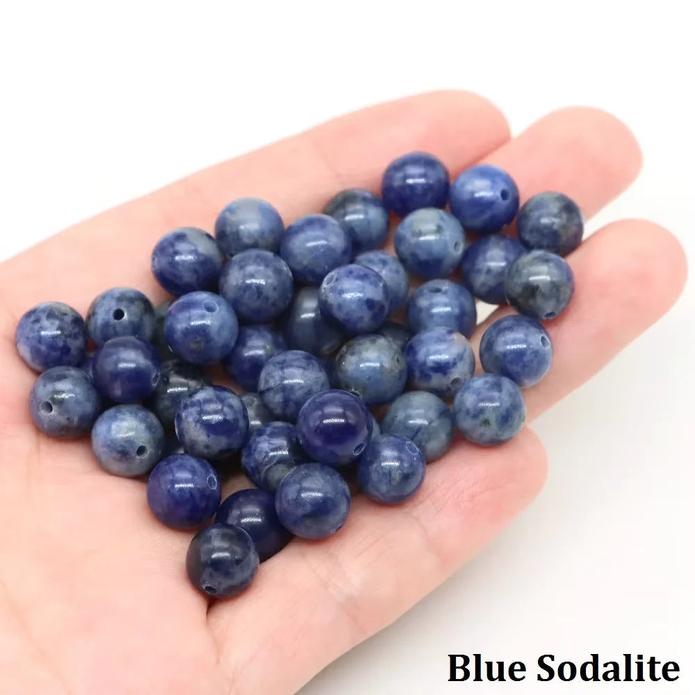 A handful of round blue sodalite beads is held in a person's hand.