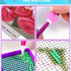 Diamond painting kit showing a pink fabric piece, a purple brush, and green beads on a grid background.