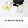A black travel organizer bag is shown open, containing baby necessities like wipes, a small toy, and other items.