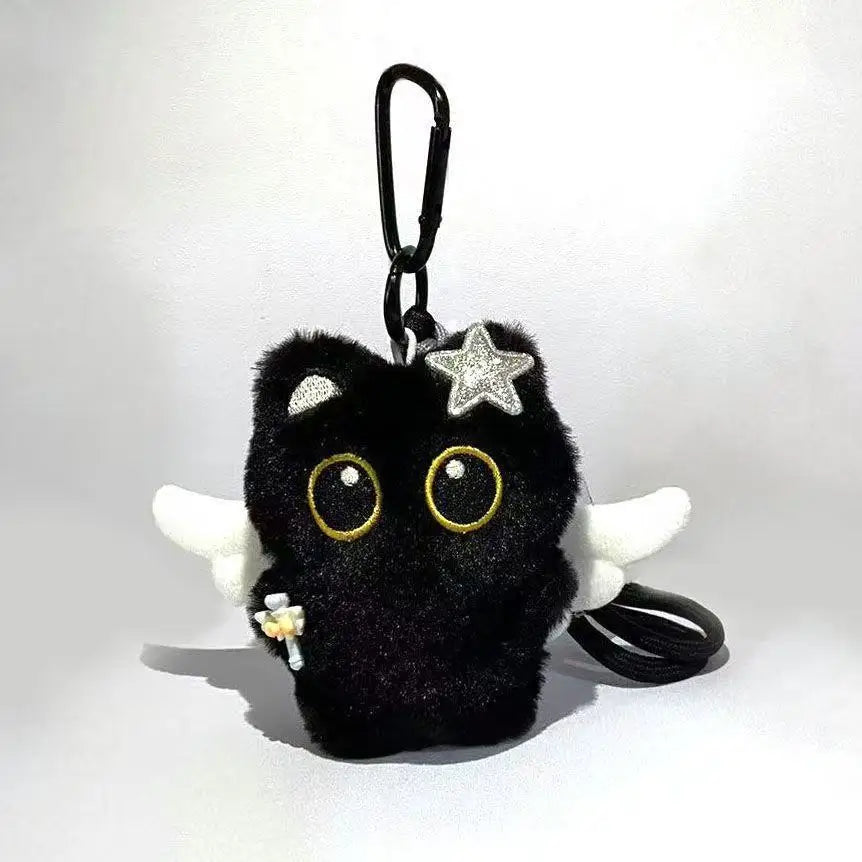 A black plush cat keychain charm with gold eyes and a silver star accent.