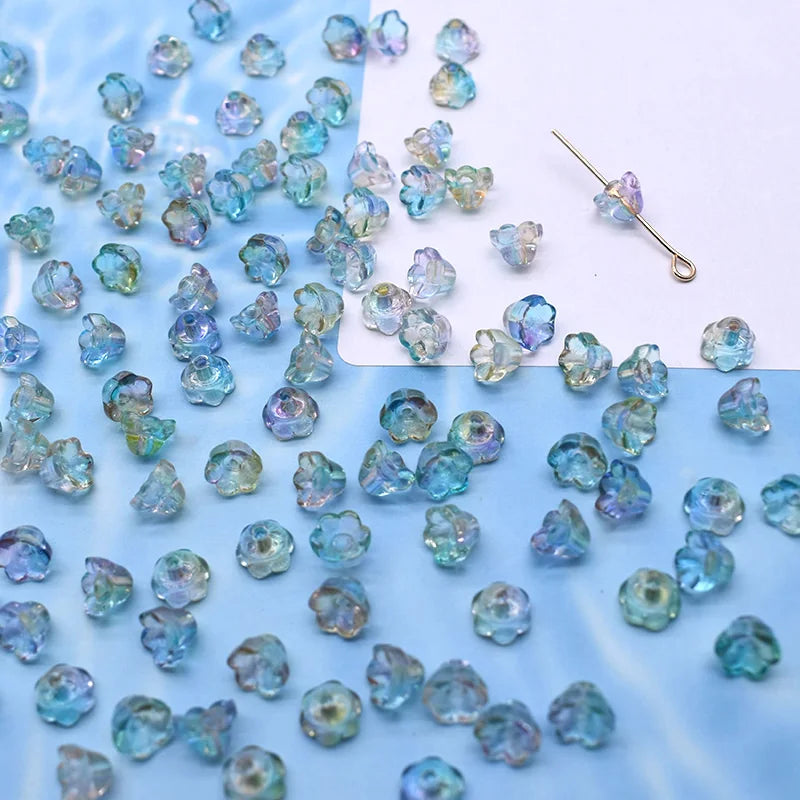 A collection of small, colorful glass beads in shades of blue and purple scattered on a white surface.