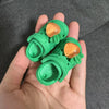 A pair of bright green fashion slippers for 1/6 BJD dolls with gold accents being held in a hand.