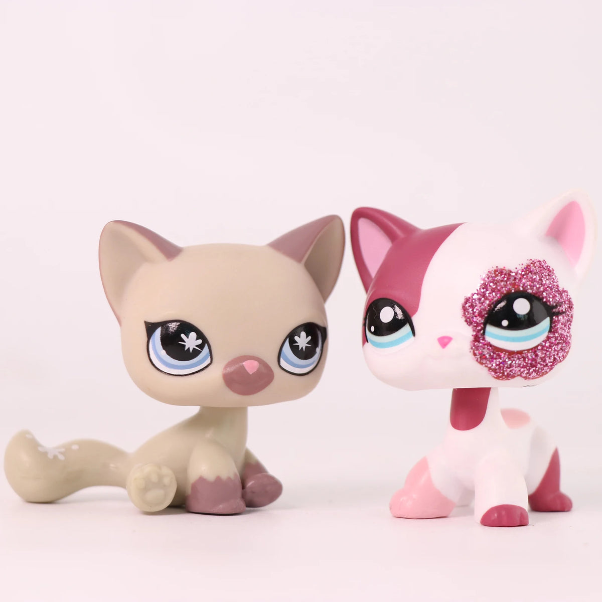 A light beige shorthair cat bobble head figurine with pink accents and sparkly purple markings.
