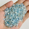 A handful of light blue to clear tumbled stone chips for jewelry making and home decor