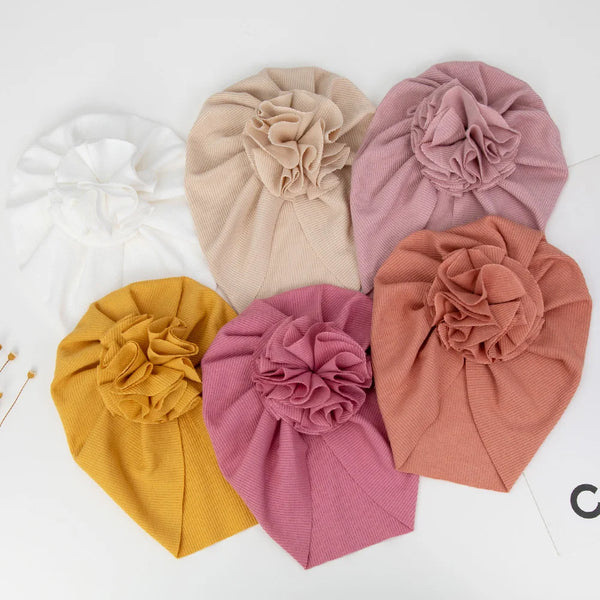 Eine Kollektion von fünf handgemachten Baumwoll-Blüten-Baby-Headwraps in Beige-, Rosa- und Gelbtönen.