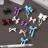 A collection of silicone bowknot nail molds in various colors including purple, blue, pink, and white, displayed on a dark su