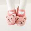 Pair of pink fuzzy cartoon bear baby booties with white socks and pink ribbon accents.