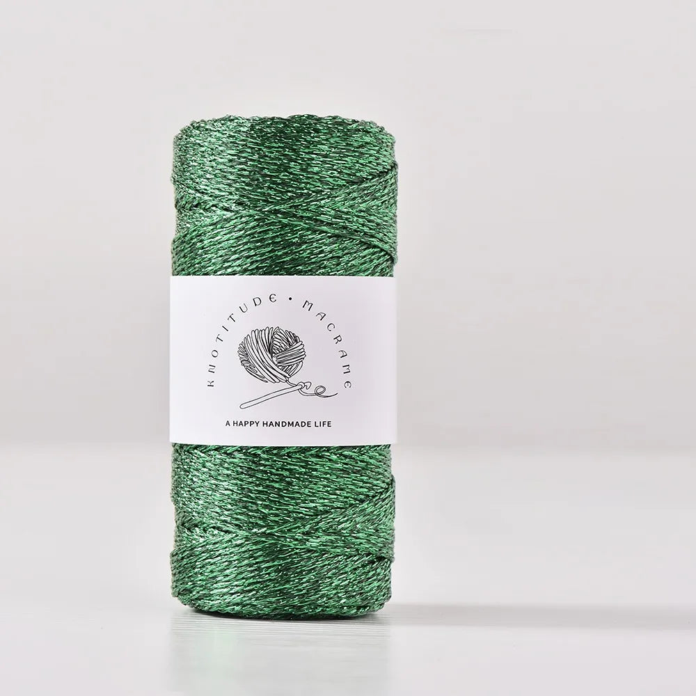 A spool of metallic green yarn for knitting and crochet with a white label.
