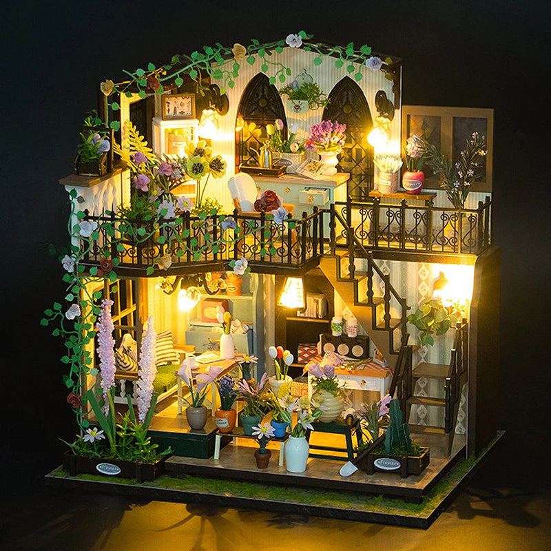 A detailed miniature dollhouse kit featuring furniture, greenery, and warm lighting.