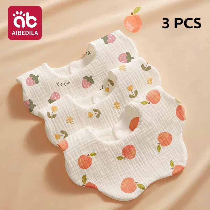 Three white cotton gauze baby bibs with strawberry and leaf patterns are displayed on a beige background.