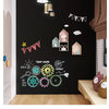 A dark wall decorated with various chalk drawings and decorative elements like clouds and garlands for a kids' chalkboard pan