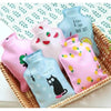 A collection of pink and blue portable hot water bottles with cozy covers are displayed in a woven basket.