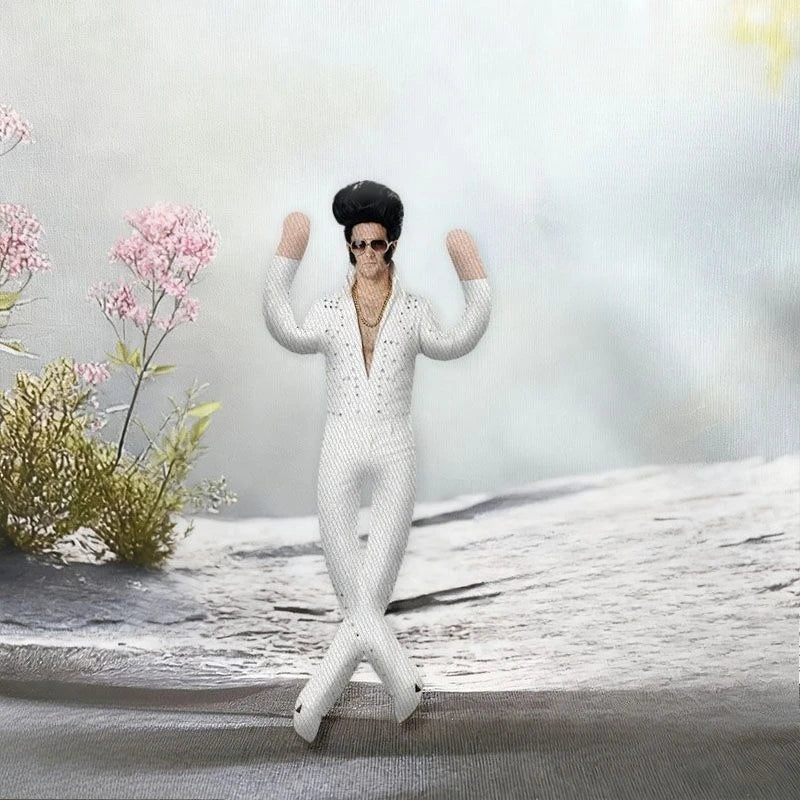A white plush doll resembling Elvis Presley with black hair and sunglasses standing on a snowy surface.