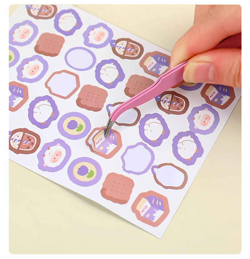 A hand uses a pink precision stainless steel tweezer to pick up a piece of food from a patterned paper.